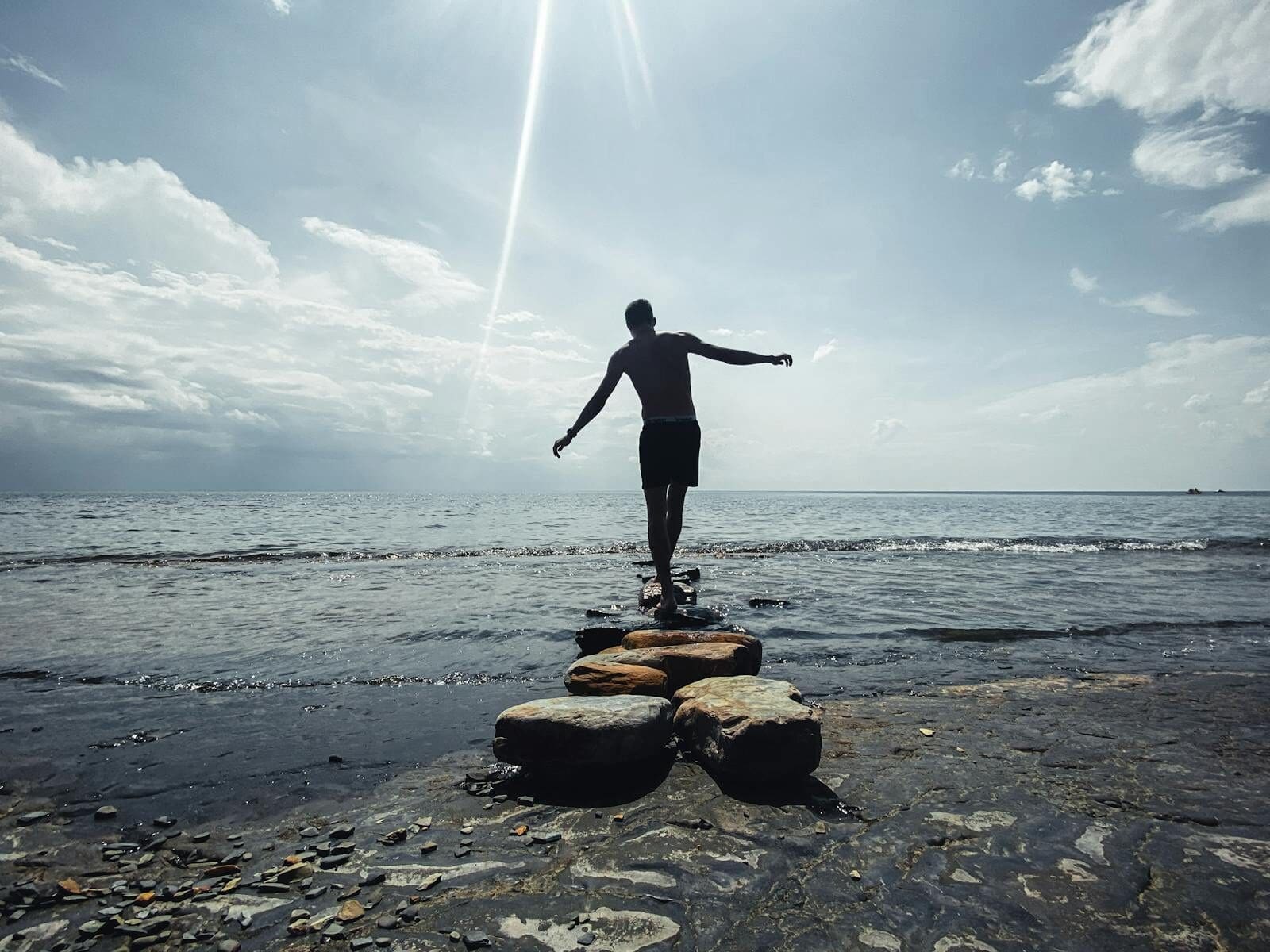 Silhouette of a man balancing on rocks by the sea at sunset, Sputnik, Russia.