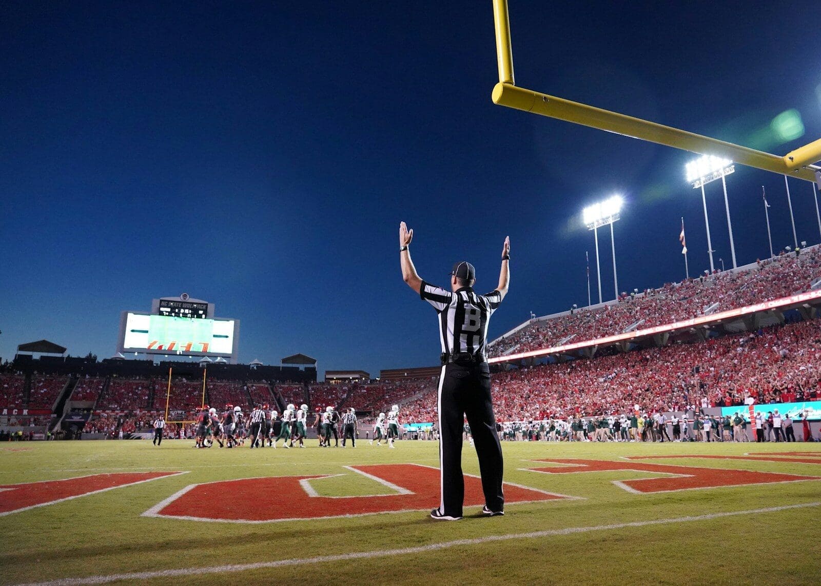 a football referee standing on a field with his arms in the air